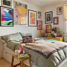 a bed sitting in a bedroom next to a window with pictures on the wall above it