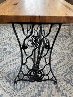 an old sewing machine is sitting on the floor next to a table with wood top