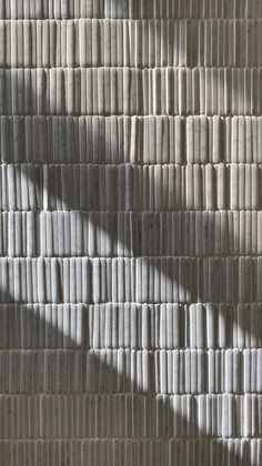 the shadow of a person standing in front of a wall made out of strips of paper