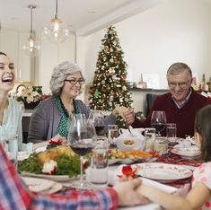 a group of people sitting around a table with food and wine in front of them