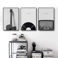 three black and white posters hanging on the wall next to a table with some books