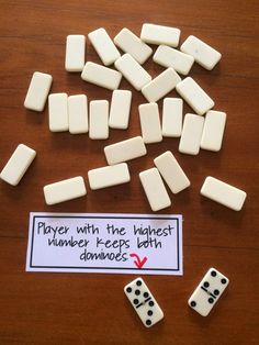 some dices are laying on a table with a sign that says player with the highest number keep both dominos