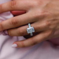 a close up of a person's hand with a ring on their finger and an engagement ring in the other hand