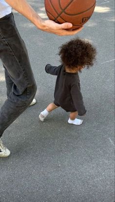 a man holding a basketball with a small child