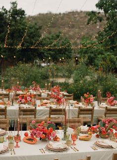 an outdoor dining area with tables and chairs covered in white tablecloths, flowers and candles