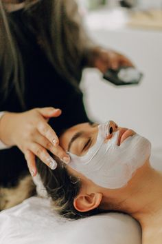 a woman getting facial mask on her face with a remote control in front of her