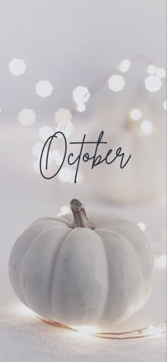 a white pumpkin sitting on top of a table with the words october written above it