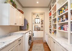 a laundry room filled with lots of white cupboards and shelves next to a washer and dryer