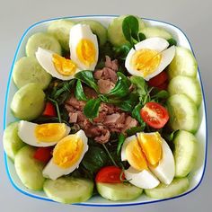 a bowl filled with sliced cucumbers, hard boiled eggs and other veggies