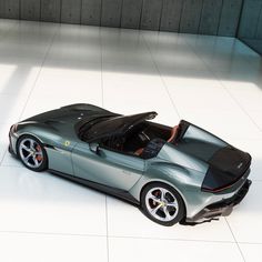 a silver sports car parked in a room with white tiles on the floor and walls