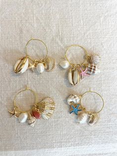 four seashells and starfish hoop earrings on a white cloth with gold wire