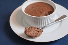 a bowl of chocolate pudding on a plate with a spoon