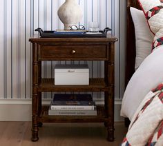 a bedside table with books and a vase on it