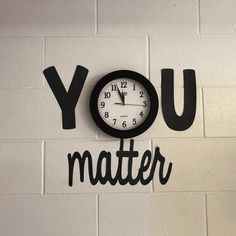 a clock mounted to the side of a white brick wall that says you matter on it