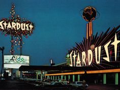 the marquee for stardust is lit up at night with cars parked in front