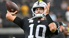 a man holding a football in his right hand and wearing a helmet with the number 10 on it