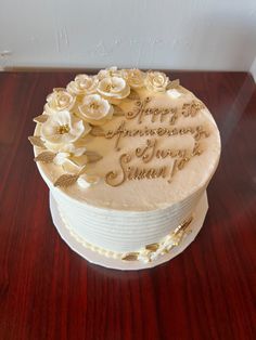 a white cake with flowers on it sitting on top of a wooden table next to a wall