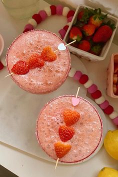 two drinks with strawberries on the rims