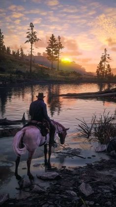 a man riding on the back of a horse next to a body of water at sunset