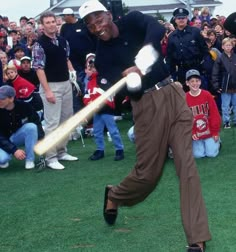 a man hitting a baseball with a bat in front of a large group of people