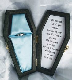 an open box with a ring inside on a white cloth covered tablecloth, the lid opened to reveal a poem in it