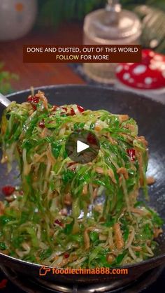 a wok filled with noodles and vegetables on top of a table