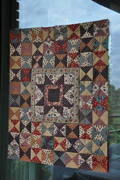 an old quilt hanging on the window sill