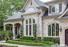 a large brick house with lots of windows and bushes around it's front entrance