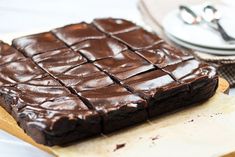 a chocolate brownie sitting on top of a table next to a plate with silverware