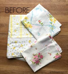 four napkins with flowers on them sitting on top of a wooden table