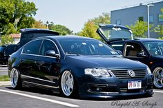 two black cars parked in a parking lot next to each other with their doors open