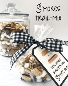 two glass jars filled with marshmallows next to a tag that says smores trail mix