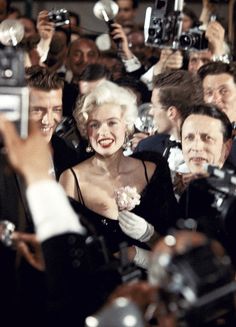 marilyn monroe is surrounded by photographers at an event in front of the camera man and woman