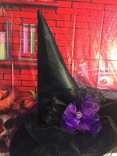 a black witches hat with purple flowers on it sitting in front of a red brick wall