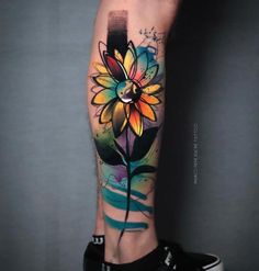 a person with a colorful flower tattoo on their leg