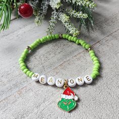 You're a mean one, Mr. Grinch! Add this must-have Grinch inspired bracelet to your Christmas collection. Design includes:  *Green and gold acrylic beads with seasonal colors *Lettered beads spelling out "mean one" *Goldtone colored enamel Grinch charm *Adjustable and stretchy style (7.5 in.) Wear as a single or stack with other bracelets. Treat yourself or gift to a special someone. Grinch Bracelet, Friendship Bracelets Ideas, Bracelet Business, Bracelet With Beads, Cute Friendship Bracelets, Mr Grinch, Beaded Projects, Cute Friendship, Bracelets Ideas