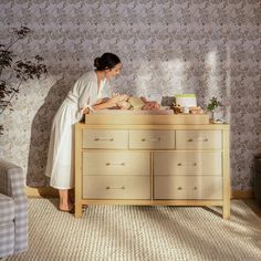 a woman in a bathrobe standing over a dresser with food on the counter