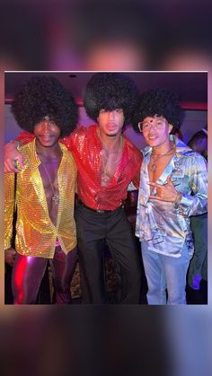 three young men dressed in disco clothes posing for a photo together at a party with one man wearing an afro wig