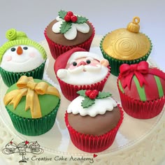 a group of cupcakes that are on top of a cake plate with santa claus