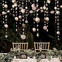 two chairs are set up for a wedding reception with ornaments hanging from the ceiling above them