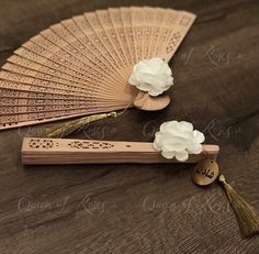 two wooden fans with flowers on them sitting on top of a wood table next to each other