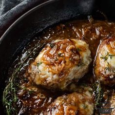 some meatballs are cooking in a pan with gravy on the top and green garnish