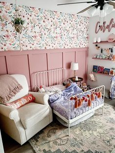 a bedroom with pink walls and floral wallpaper, two white chairs and a baby's crib