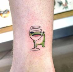 a small tattoo on the leg of a person with a glass of wine in it