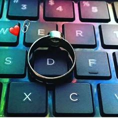 a ring sitting on top of a computer keyboard with the word love spelled below it