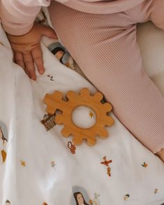 a baby laying in bed with a wooden toy