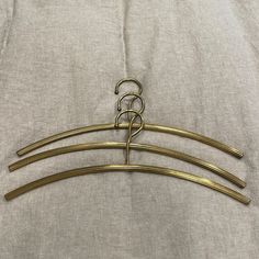 three gold colored metal hangers on a white cloth