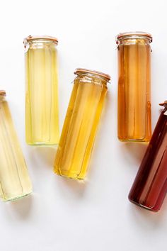 four glass jars filled with different colored liquid