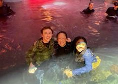 three young people in the water with their faces painted like mermaids and smiling at the camera