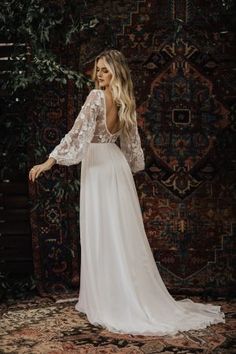 a woman in a white wedding dress standing on a rug with her back to the camera